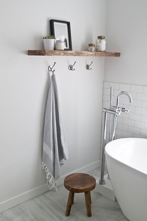 a wooden floating shelf adds texture to the bathroom decor