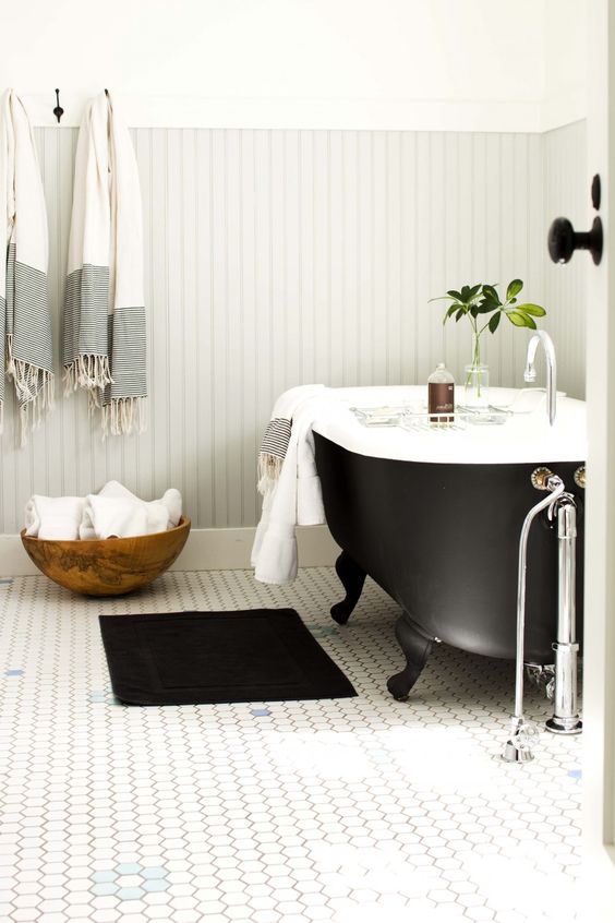 a black clawfoot bathtub with black legs makes this bathroom chic