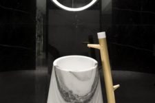 29 a white marble sink of an eye-catchy shape with a wooden faucet next to it