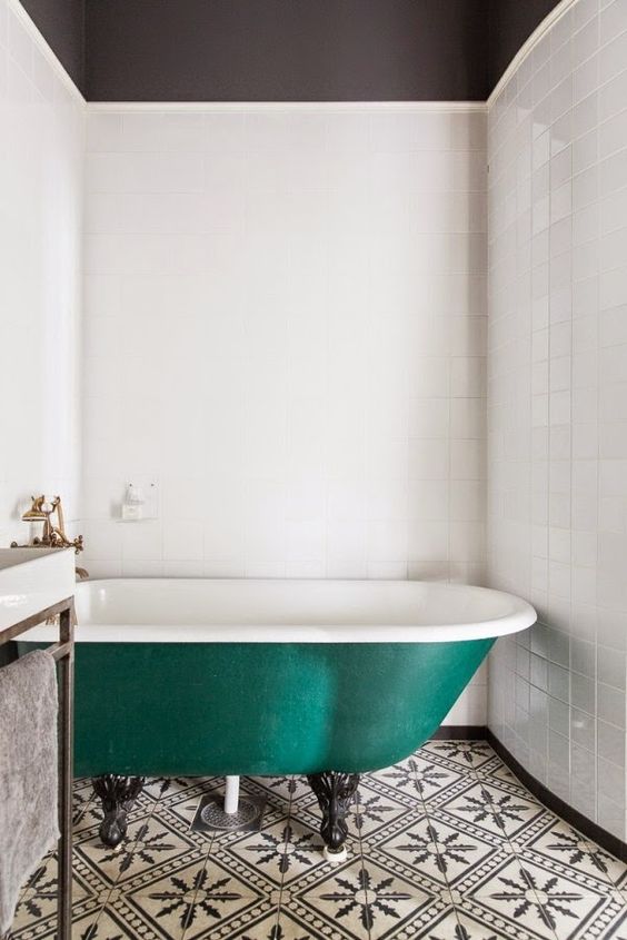 a black and white bathroom with an emerald bathtub on black clawfoot legs to make a statement