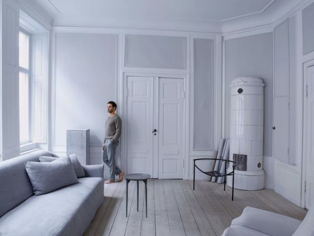 grey wooden floors The living room features wooden floors, grey walls and furniture and a vintage white hearth, windows let much light in