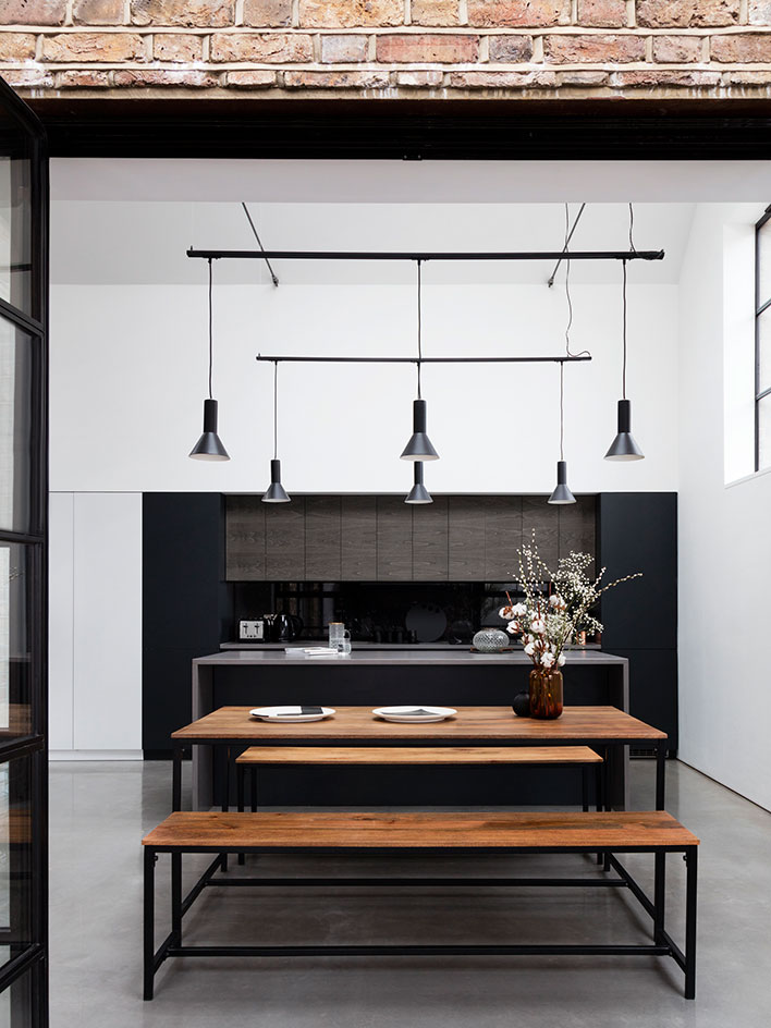 The dining space features a stained wooden table and benches with black framing