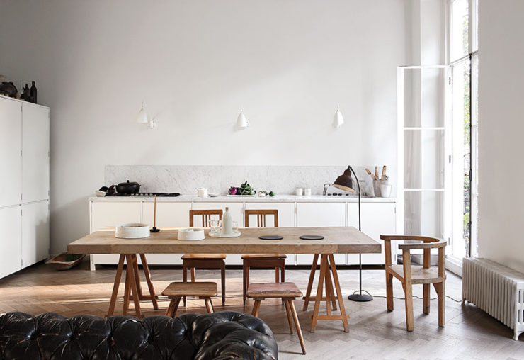 The kitchen and dining space are united in one, with white cabinets and light-colored wooden dining set