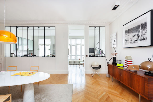 The dining space is separated with framed glass partitions from the kitchen and features mid-century modern furniture