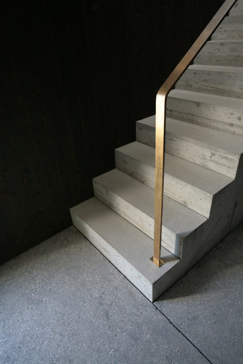 The staircase is concrete. with minimalist brass rails