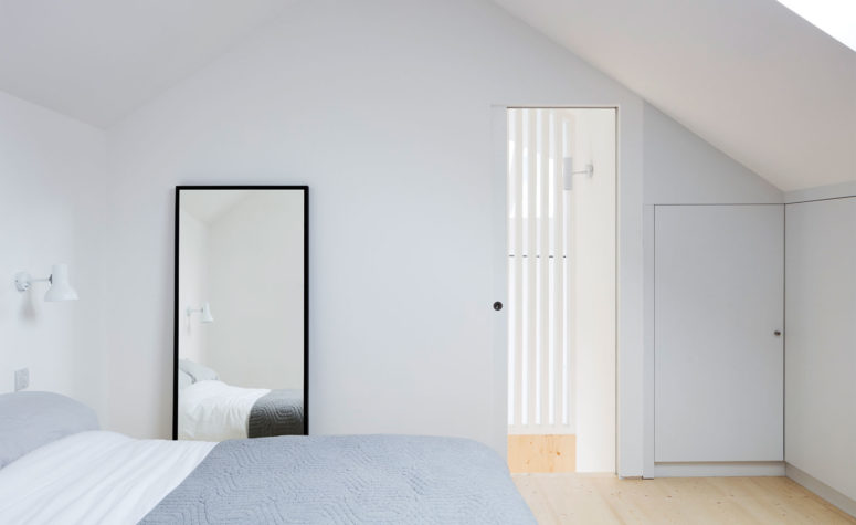 The bedroom is clam and peaceful with light-colored wooden floors and white walls, only a bed and a mirror are here