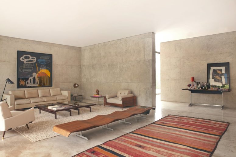 concrete look The living room features comfy neutral-colored furniture, a bold artwork piece and some rugs that soften the rough concrete look