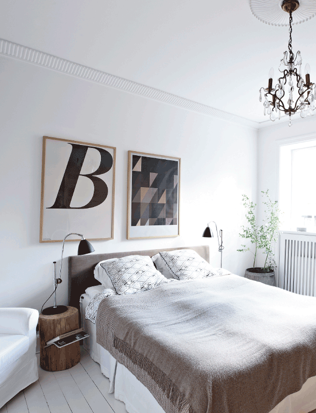 The master bedroom features a cozy bed, wooden log bedside tables and some graphic artworks, this is pure eclectics done right