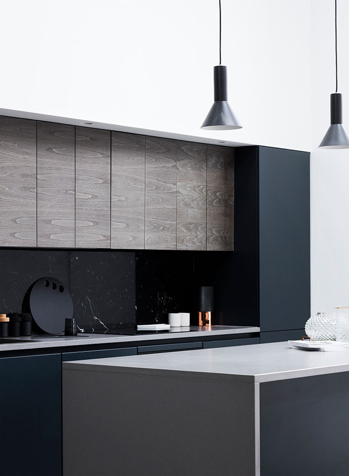 The kitchen is dark and masculine, with a cool texture combo of black marble, concrete and dark stained wood