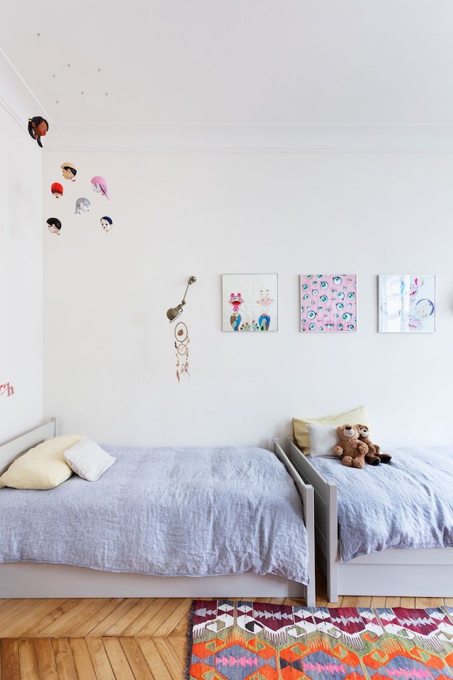 This is a shared kid's room with two beds and kids' artworks