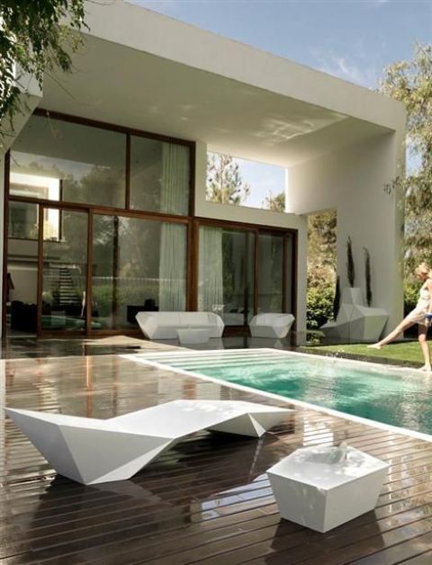 a modern white sculptural lounger and a table for a pool area