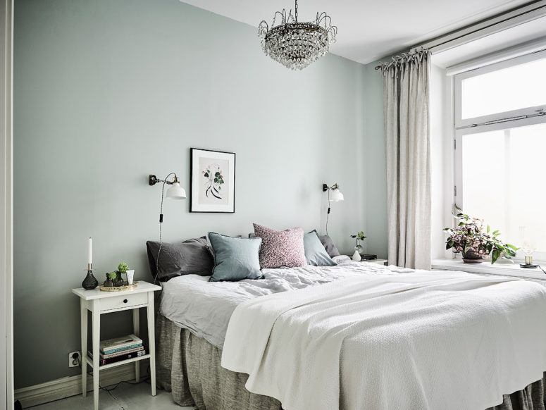 The master bedroom features green walls, a large crystal chandelier and soft textiles