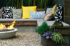 11 a concrete bench with grey upholstery and colorful pillows