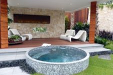 11 a round jacuzzi clad with small blue tiles in front of a deck
