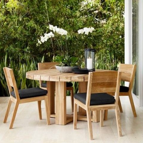 light-colored round wooden table with matching chairs and black upholstery