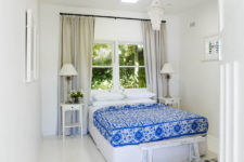 The second bedroom is all-white with a bold patterned bedspread