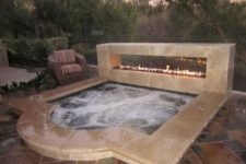 15 a sunken jacuzzi with a stone edge and a fireplace next to it for a dramatic look