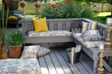 21 L-shaped grey wooden bench with cushions and pillows and a garland over it