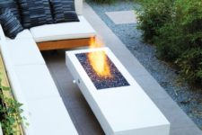 23 modern outdoor space with a L-shaped bench with white cushions and a modern white table with a fireplace