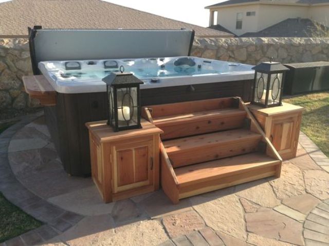 a jacuzzi with wooden stairs and lanterns on the corners