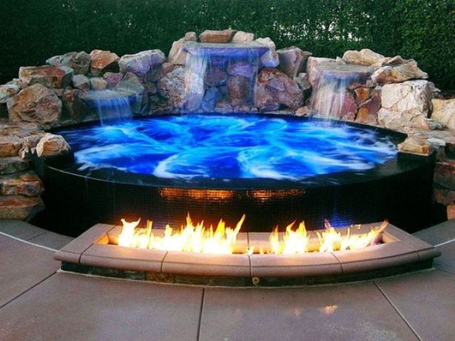 a spectacular blue jacuzzi clad with black tiles and with waterfalls