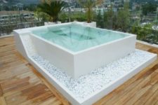 27 a square jacuzzi decorated with white pebbles on a wooden deck looks very natural and refined