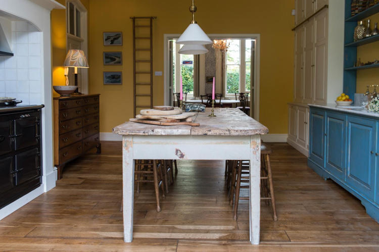 All the walls are sunny yellow, the shelving unit is bold blue, and there are some cream-colored cupboards