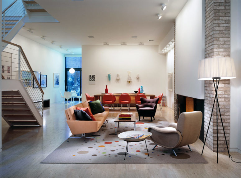 a living room united with a dining area The living room is merged with a dining area, and you can see a cool fireplace with brick decor and designer furniture in hot red and orange