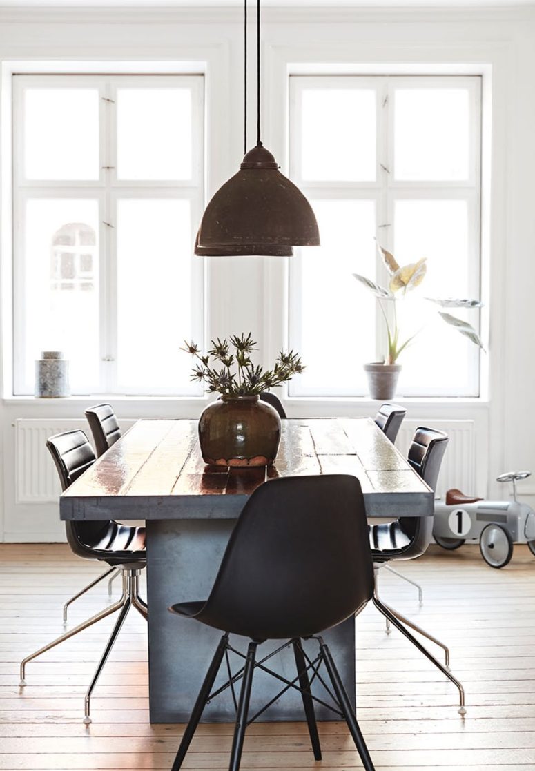 The dining area has a rustic wooden plank table with a concrete base, black industrial chairs and vitnage lamps