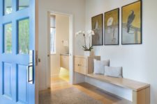03 The entryway fetures artworks with light-colored wooden furniture, modern and chic