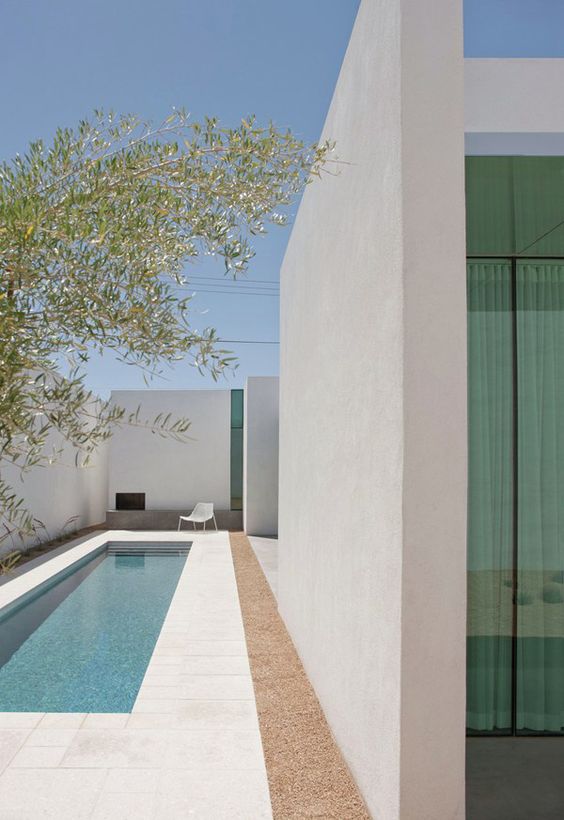 a clean minimalist backyard with a small narrow pool clad with white tiles