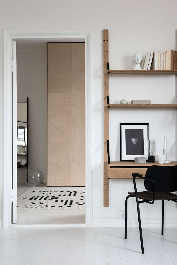 The home office has a cool wall-mounted desk and shelves and a simple leather black chair