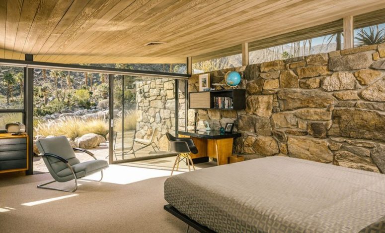 stone wall in a bedroom The master bedroom shows the same ceiling and a stone clad wall, comfy furniture in warm shades and an entrance to the terrace, this glazed wall lets enjoying the views