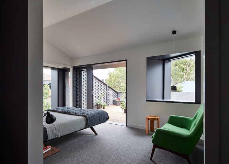 The bedroom is done in black and white, it's fully opened to outdoors with doors and windows and there's a bold green chair for a statement