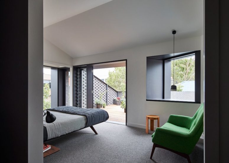 The bedroom is done in black and white, it's fully opened to outdoors with doors and windows and there's a bold green chair for a statement The bedroom is done in black and white, it's fully opened to outdoors with doors and windows and there's a bold green chair for a statement