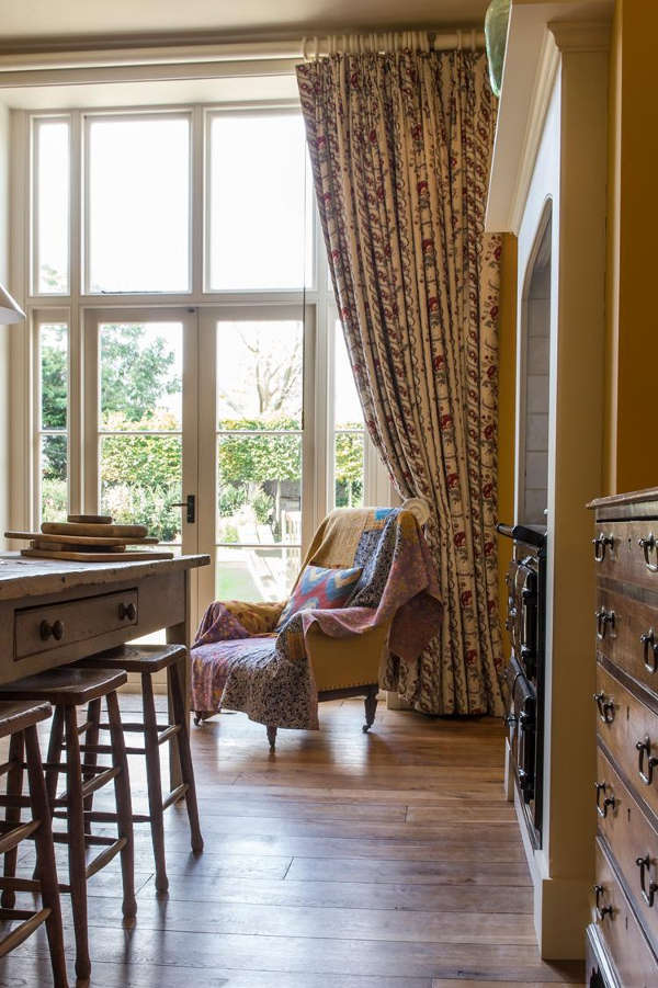 The space is made cozier with a wooden dresser, curtains and a vintage upholstered chair with carved legs