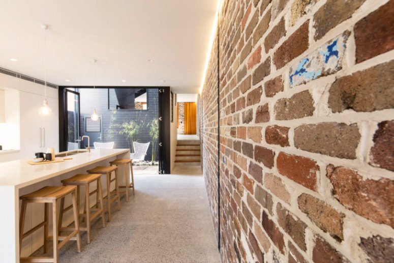 The kitchen is minimalist and industrial, with brick walls and sleek white furniture and kitchen island