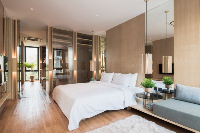The bedroom features lots of warm-colored wood for comfort and mirrors and glazings to make it look bigger