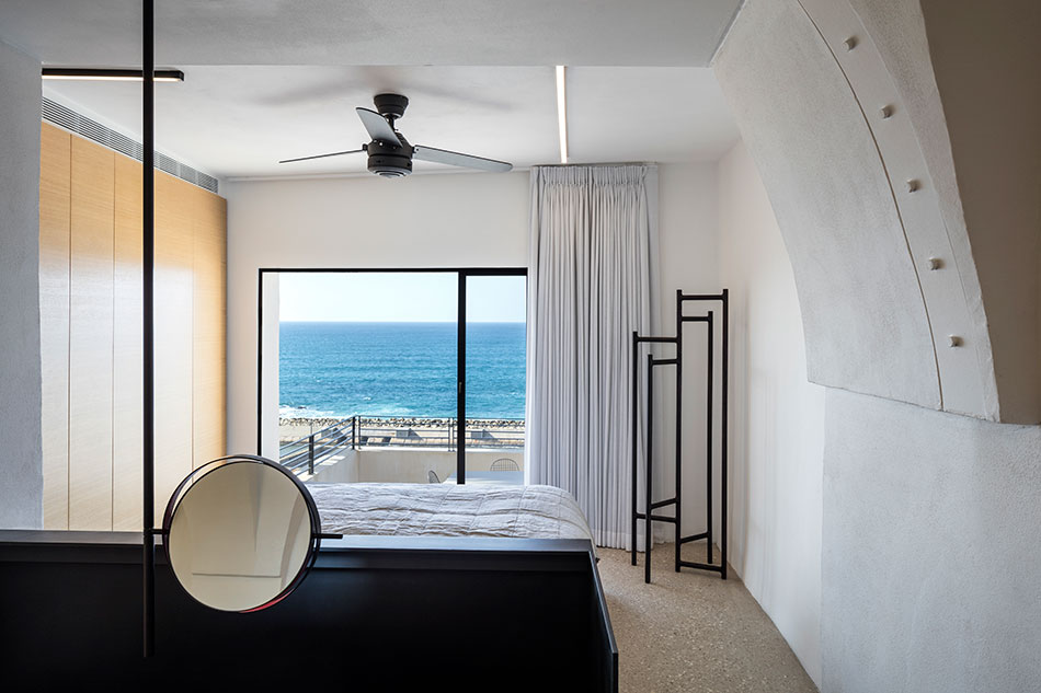 The bedroom is white, with a black bed, eye catchy black clothes rack and a light veneer wardrobe, the sea view is amazing