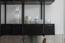 09 The kitchen cabinets and countertops are made of blackened metal, the shelves have a ligthweight look due to the perforated design