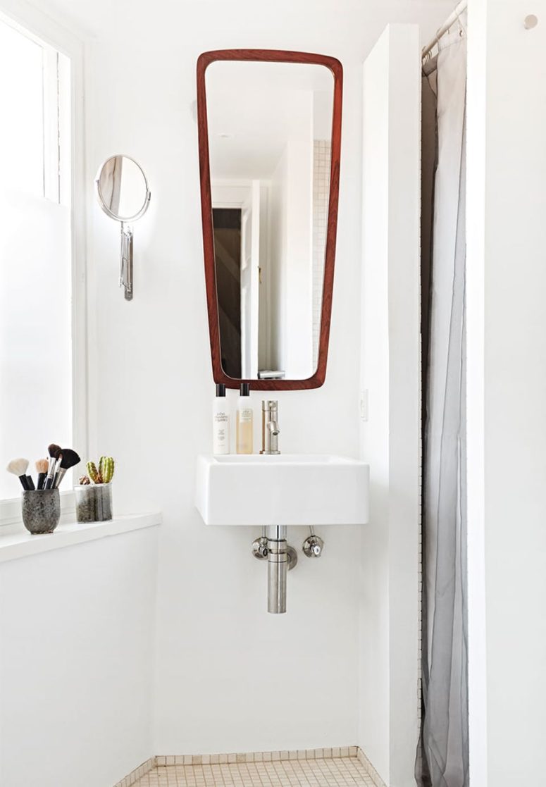 The bathroom is all-white, with a view and an eye-catchy mirror in a wooden frame