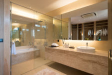 10 The bathroom is clad with light-colored stone, there’s a shower and a bathtub