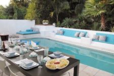 10 a gorgeous white backyard with cushioned benches and a narrow pool