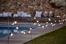 10 bistro bulb fairylights attached to hooks along the whole pool