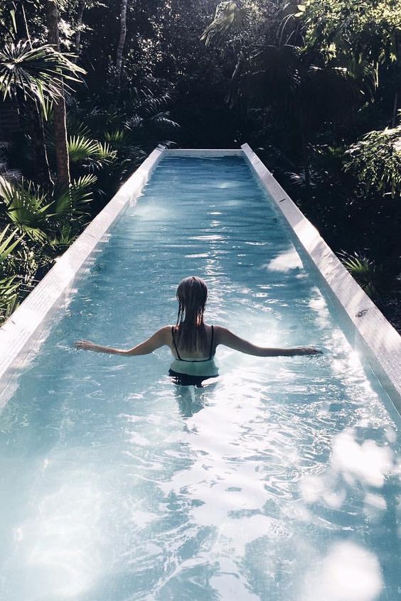 a gorgeous white clad narrow pool in a tropical garden