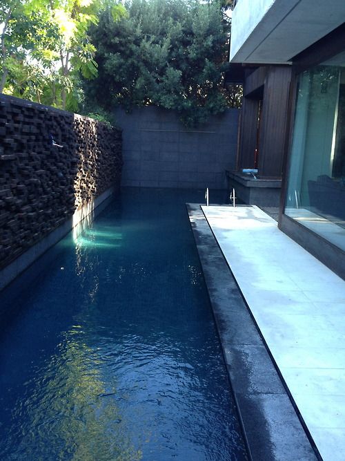 a narrow pool that goes along the whole house and keeps privacy with a stone wall