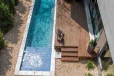 28 narrow backyard pool clad with white tiles next to a wooden deck