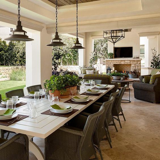 a beautiful outdoor covered porch with a large table for entertaining and a separate living area with fireplace - feels like an indoor extension