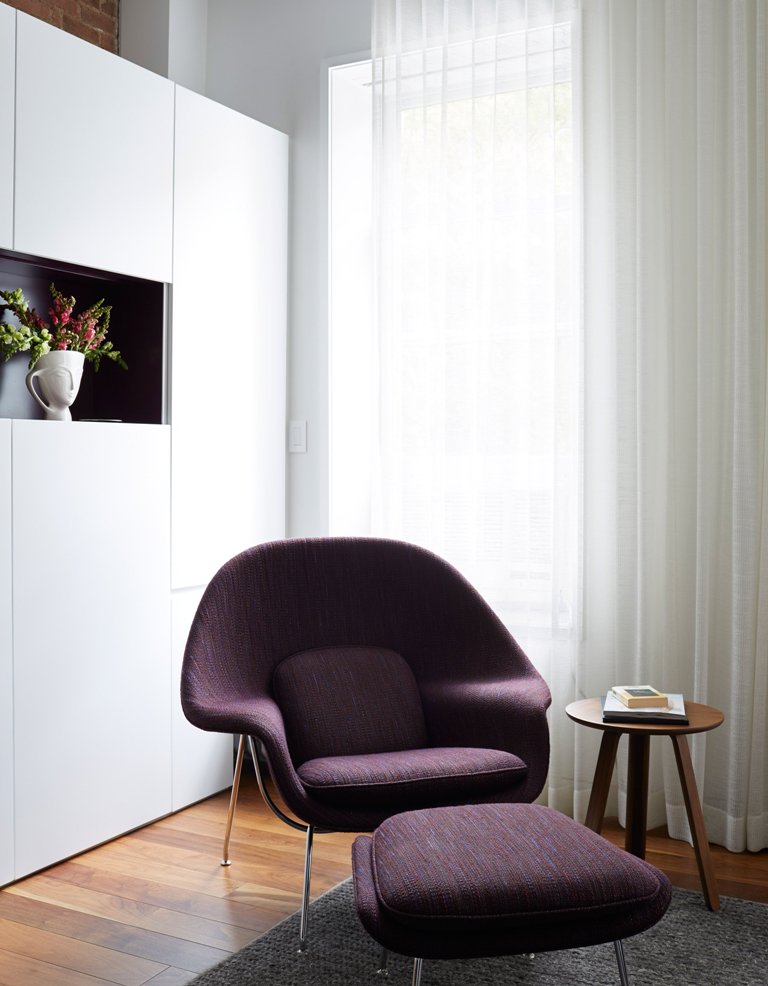 A long range of white cabinets along one wall gives much storage space and there's an open purple niche