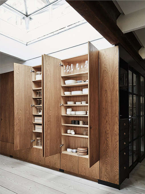 The built-in tall wooden cabinets are a comfy solution to accomodate a lot of things